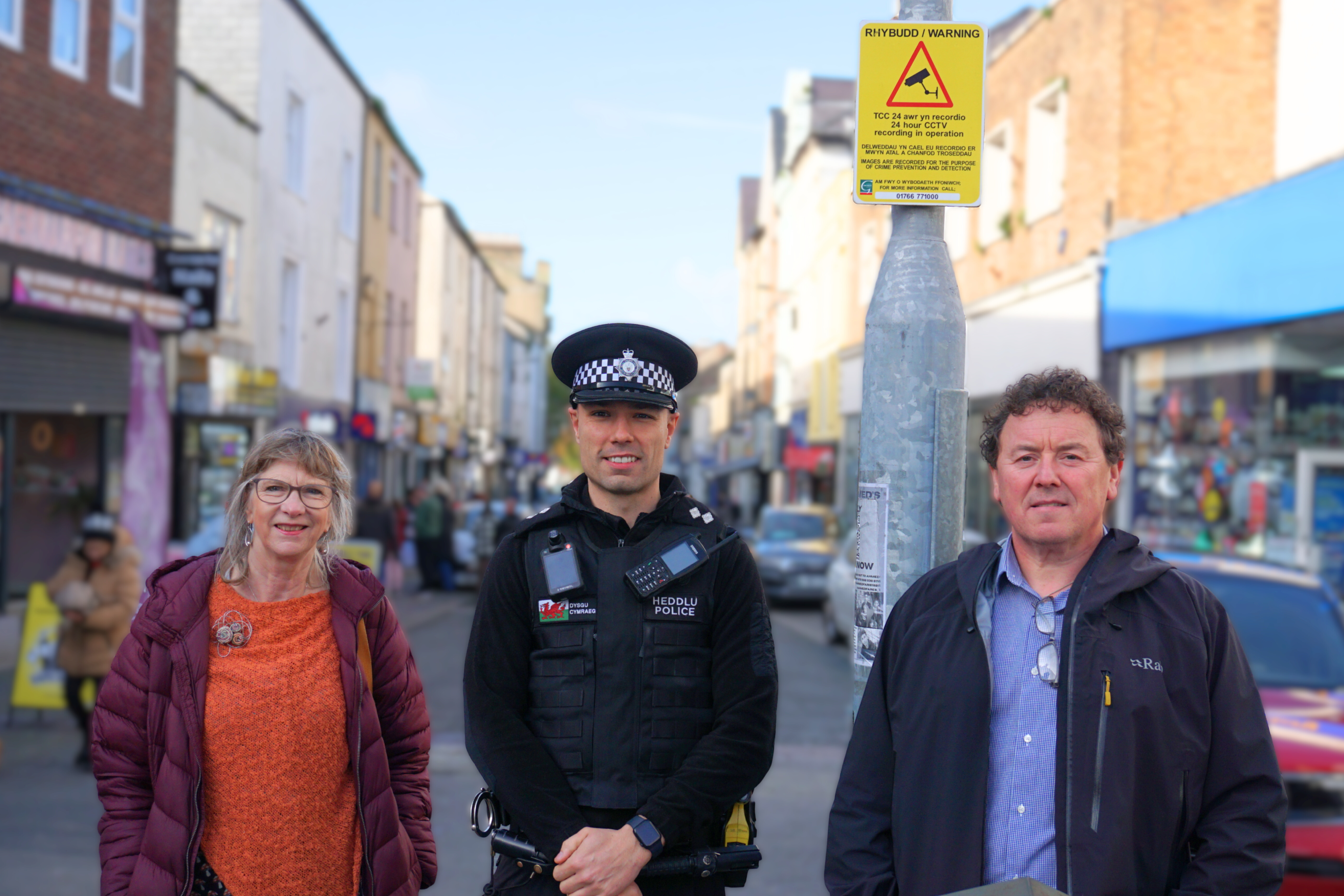 Dau berson a swyddog o'r Heddlu ar stryd Caernarfon
