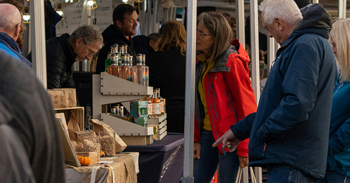 A busy market with people looking at produce or walking around.